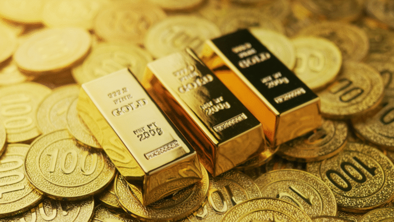 3 sztabki złota na tle monet ze złota